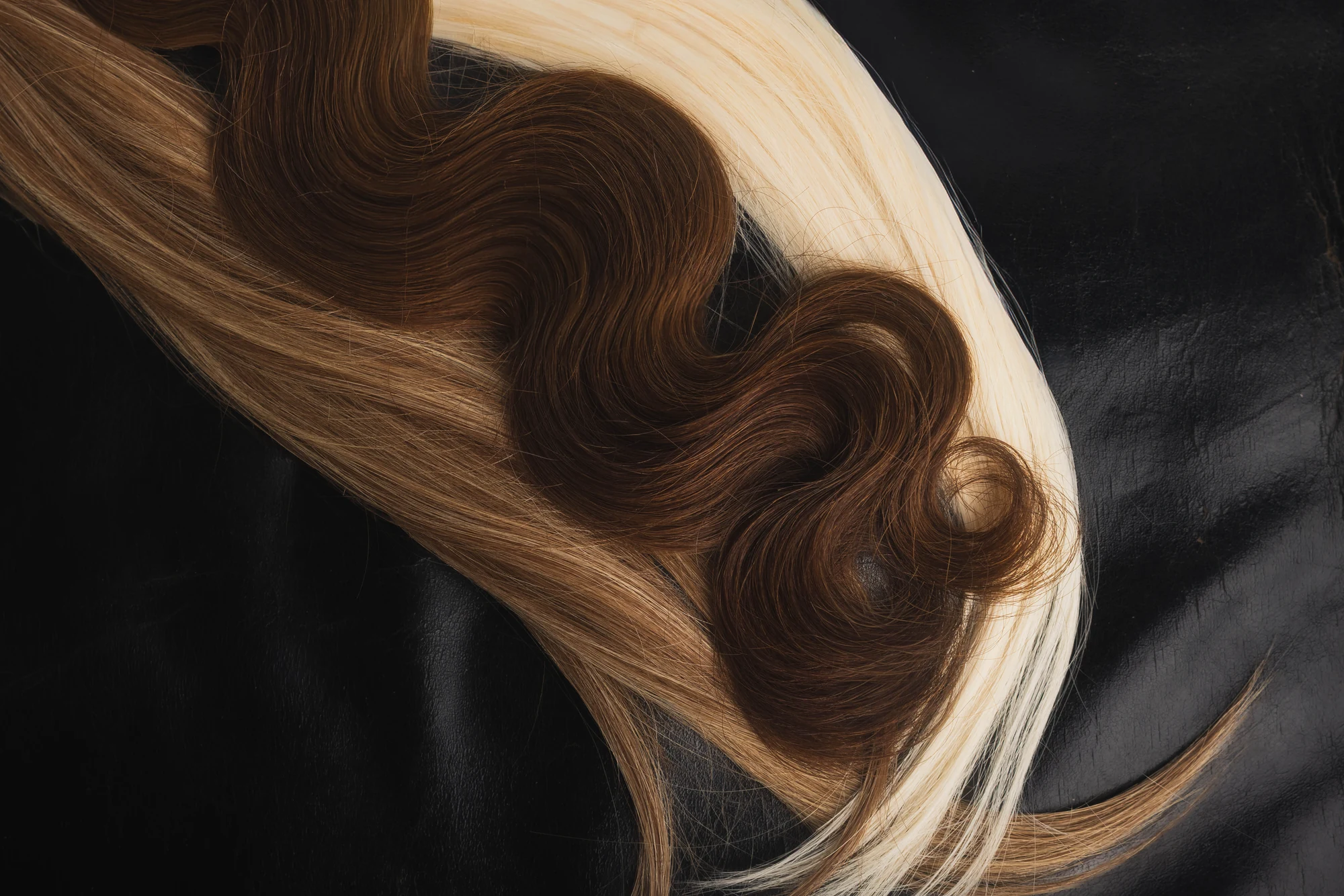 Brown and blonde hair bundles arranged on a dark surface